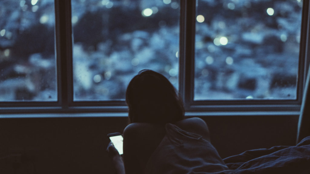 A woman in bed using her phone